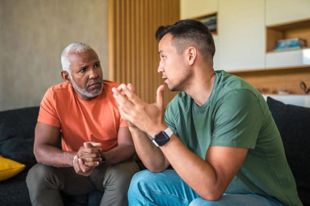 Listening to a colleague Two men talking to each other and listening carefully