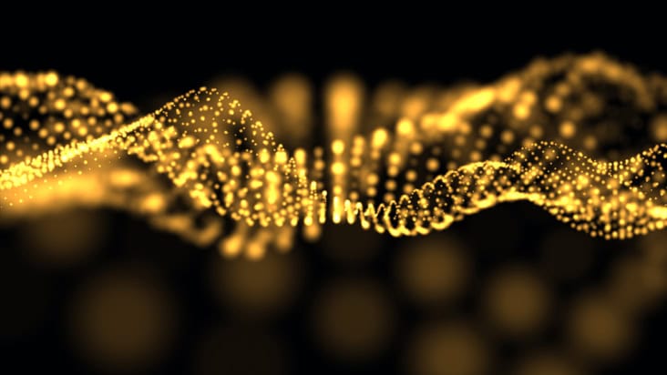 A bunch of golden dots form a wave against a black background
