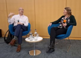 Photo of two people in chairs at a meeting.