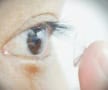 A person holding a small transparent circular-shaped object on their finger near their eye