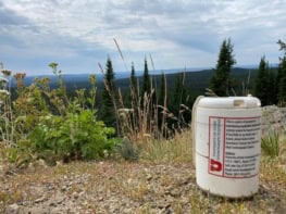 A photo of a portable seismometer outdoors with trees and grass in the background