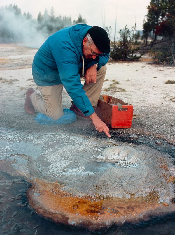 Tom Brock taking a sample from near a hot spring