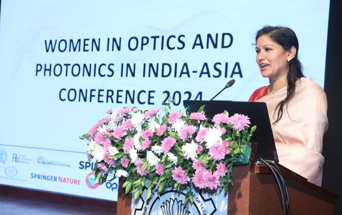 Woman speaking at a podium in front of a large screen