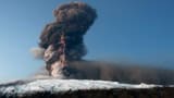Tall plume of black smoke and a fork of lightning coming from a volcano