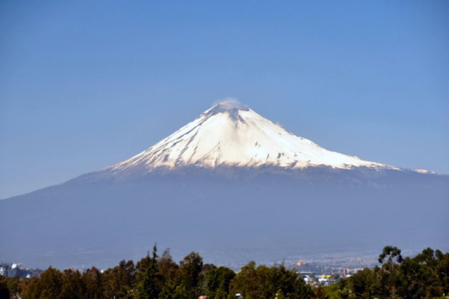 Snow-capped active volcano looming over a small town