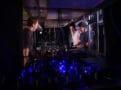 Photo of three men standing around an optical table bathed in deep blue light