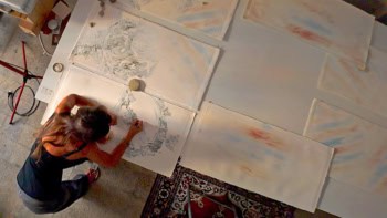 Photo looking down at the artist Serena Scapagnini as she paints in her studio