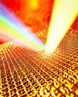 A laser superheats a sample of gold. The gold is shown as a gold-coloured lattice while the laser is a bright beam of light. A rainbow coming off the lattice represents light being emitted at different wavelengths