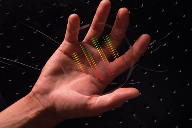 A hand holding a silicon wafer