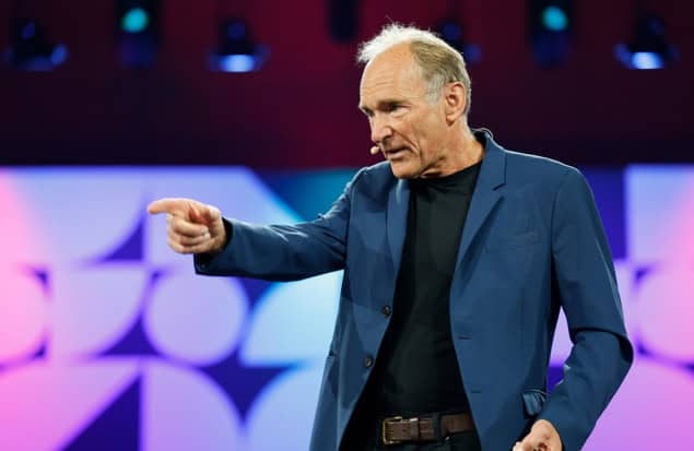 Tim Berners-Lee wearing a small head mic and gesturing on a brightly lit stage