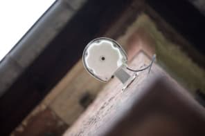 Photo of a wireless access point mounted on a building, seen from below so that it looks like an eye looking down at the viewer