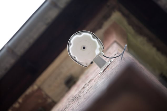 Photo of a wireless access point mounted on a building, seen from below so that it looks like an eye looking down at the viewer