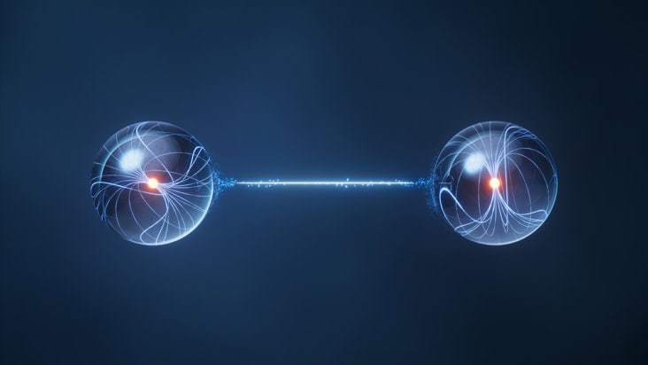 Illustration of quantum entanglement showing two crystalline spheres with glowing centres surrounded by wavy lines. The spheres are connected by a tenuous, bright line