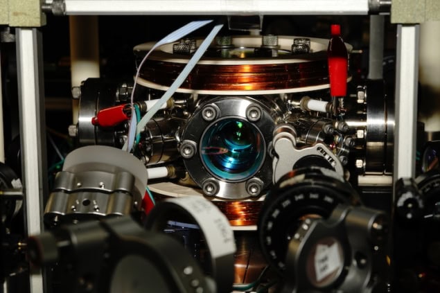 Photo of the experimental setup, a vacuum chamber surrounded by optics and magnetic coils.