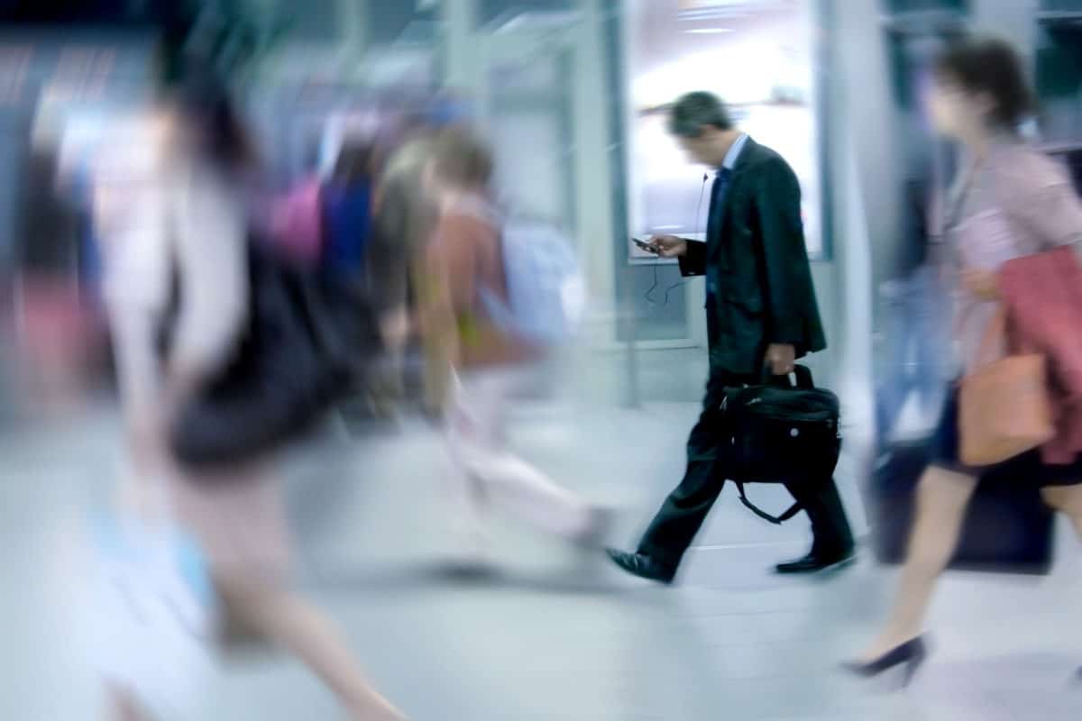 Businessman walking in a crowd looking at his phone