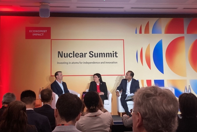 Photo of Charles Oppenheimer, Najat Mokhtar and Vijay Vaitheeswaran on stage at the Nuclear Summit in London. They're all wearing business suits and several rows of heads are in the foreground