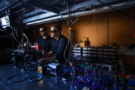 Two scientists standing at an optical bench in a semi-darkened laboratory. They're both wearing laser safety goggles and there is equipment on the bench, but not an entire bench's worth as is the case in some experiments.