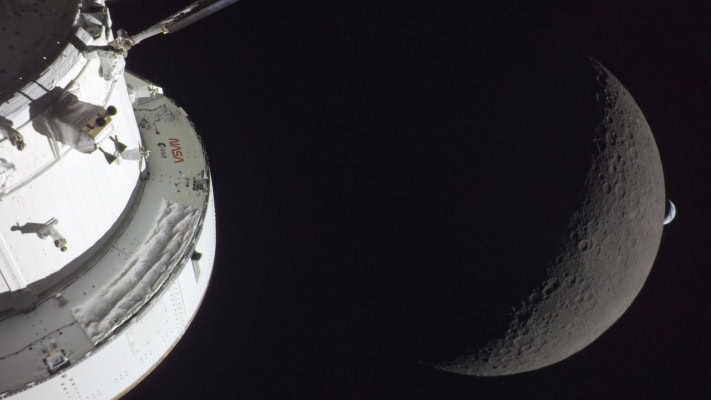 Orion module in foreground with the Moon behind and then in the far distance a crescent of Earth