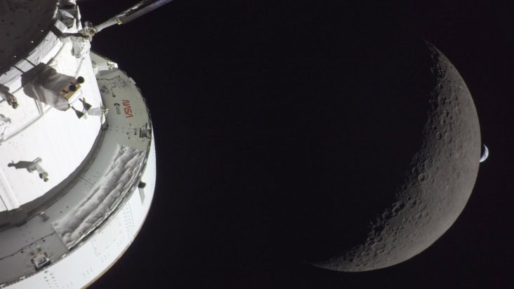 Orion module in foreground with the Moon behind and then in the far distance a crescent of Earth