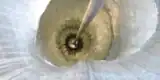 A photo of a detector buried deep in solid ice, connected to the surface by a cable