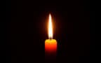 A lit candle against black background