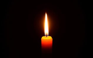 A lit candle against black background