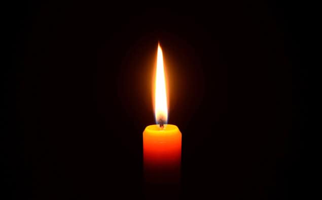 A lit candle against black background