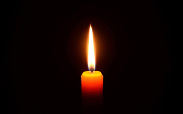 A lit candle against black background