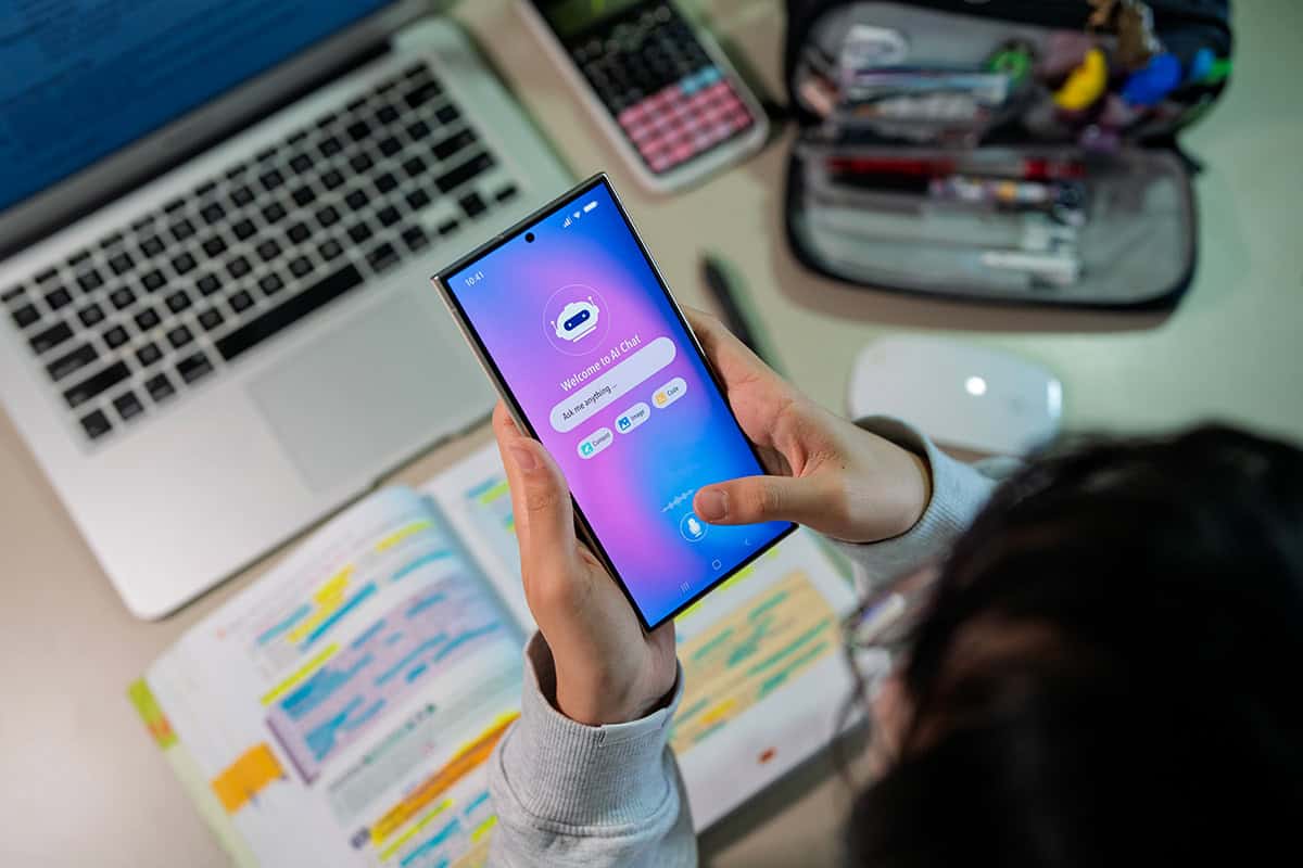 A student with an open textbook using a chatbot on their phone