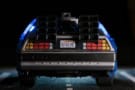 A photo of a Playmobil model of the Delorean used as a time machine in the film Back to the Future. The car has a California licence plate reading "OUTATIME" and looks like it's on a real road.