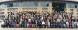 Large group of people posed in front of a modern university building