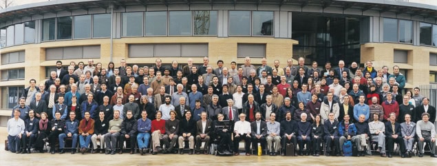 Large group of people posed in front of a modern university building