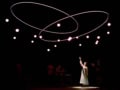 Isis Hainsworth on stage under interlocking rings and many small lights