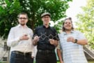 Three men holding a model of a carbon-based model. They're standing outside and there's a tree in the background