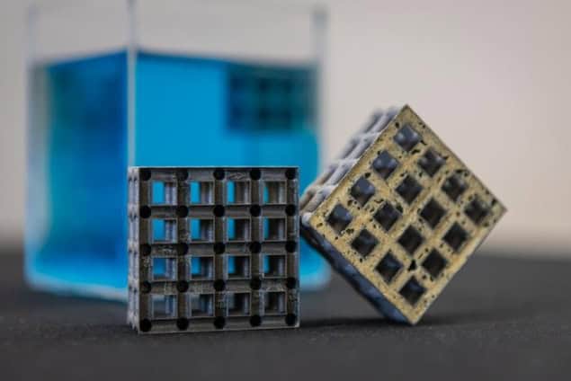Two structures made of a lattice of cubic voids. One set of voids is filled, the other isn't. A larger cube filled with blue liquid or gel is in the background